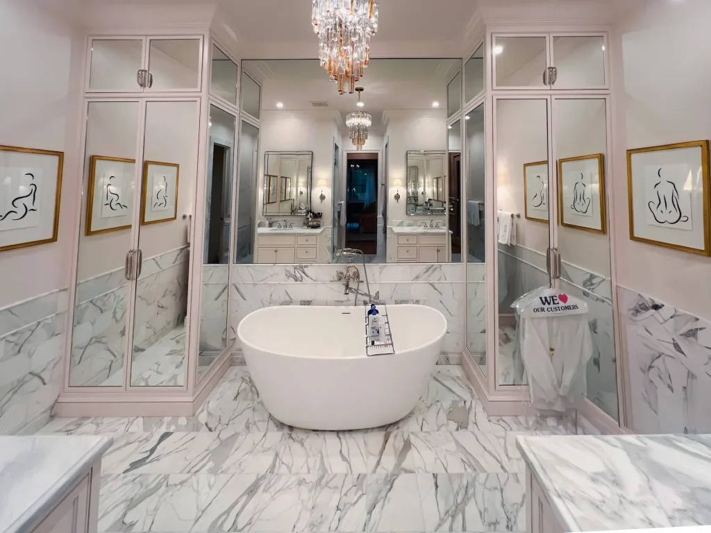 Stylish bathroom featuring crystal glass shower doors, a clawfoot bathtub, and marble flooring and walls.