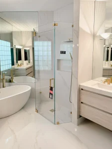 Beautiful modern glass shower with sleek, frameless design and brass hardware.