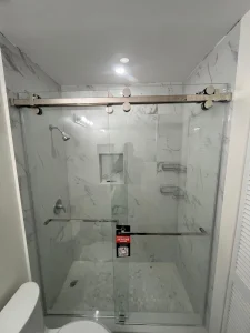 Elegant glass shower with brushed metal sliding door. Modern, durable, and stylish bathroom upgrade.