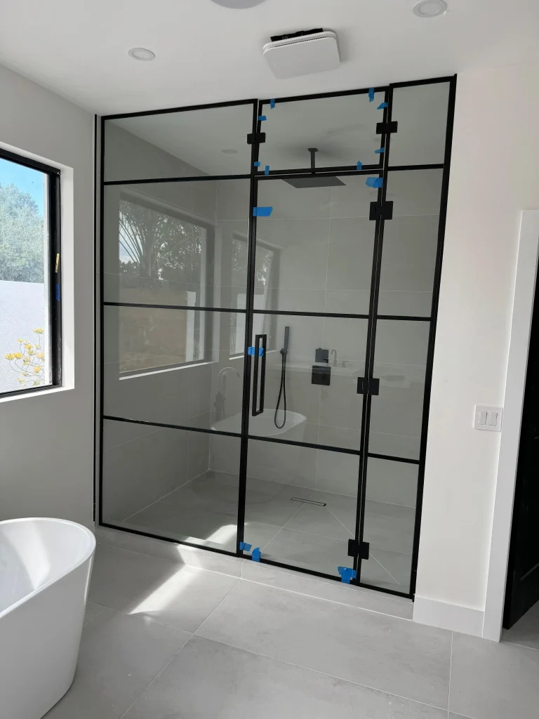 Clear glass shower door with black metal frame and handle.