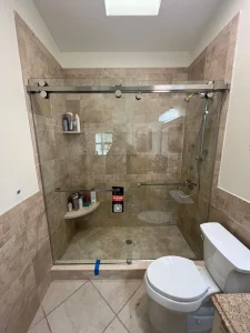Durable glass shower door with sleek metal tracks, spacious tiled shower area, and modern bathroom fixtures.