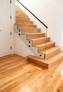 Custom glass staircase with sleek glass railing and wooden steps for modern homes.
