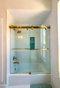 Modern glass shower enclosure with brass hardware.