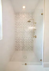 High-quality glass shower enclosure featuring gold fixtures and textured interior tiles for modern bathroom design.