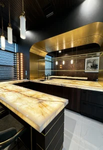 Luxurious black and gold onyx marble kitchen island with elegant lighting accents.