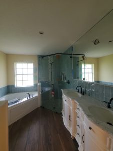 High-quality glass shower enclosure with sleek black hardware and double vanity mirror.