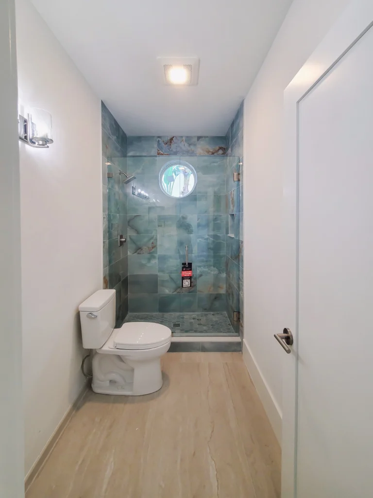 Bright bathroom featuring custom glass shower with blue marble tiles and sleek fixtures.