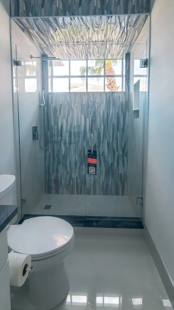 Safe, modern glass bathroom shower with textured panels and large window.