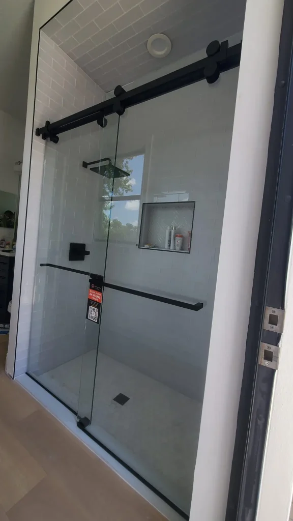 Clean glass shower door with black sliding hardware and built-in niche.