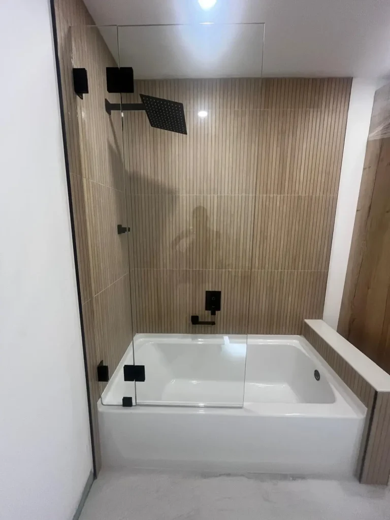 High-quality glass shower enclosure with black fixtures and wood-paneled wall. Modern, sleek design for bathrooms.