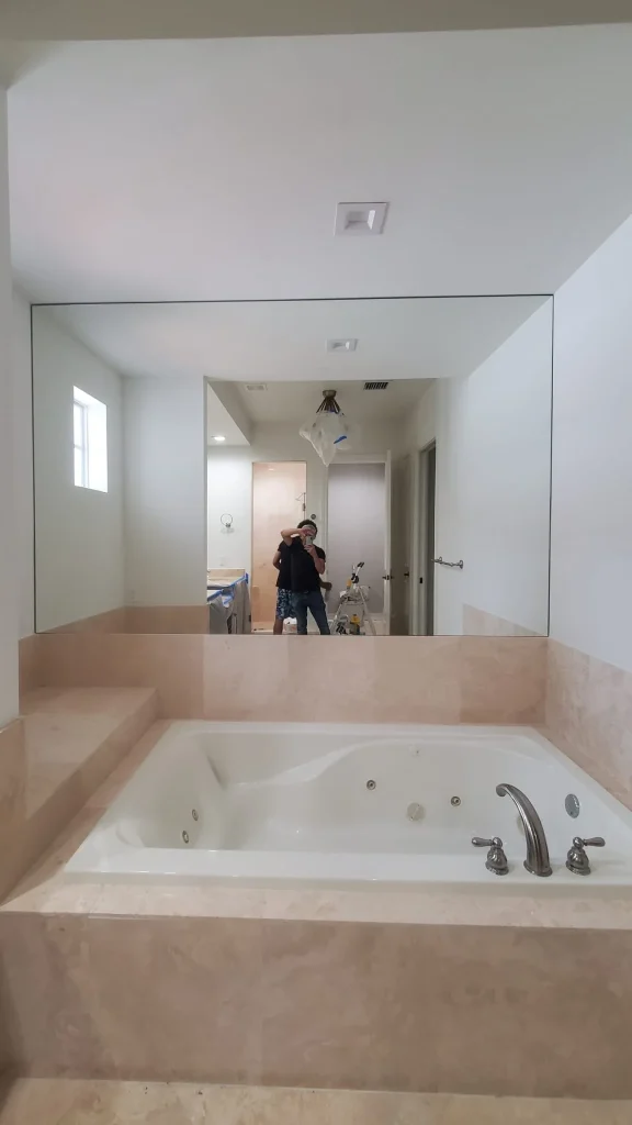 Mirror wall in bathroom with Jacuzzi tub.