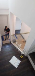 Wide view of glass railing being installed at staircase.