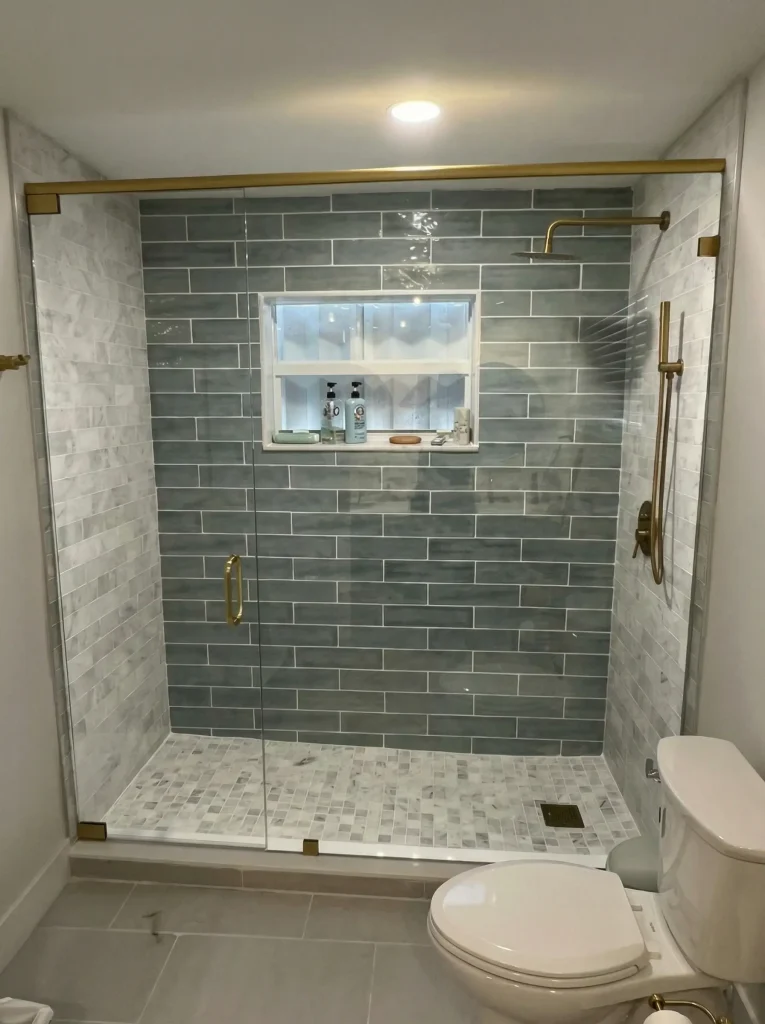 Frameless glass door and panel shower with brass hardware and green subway tile, 39th Street residence