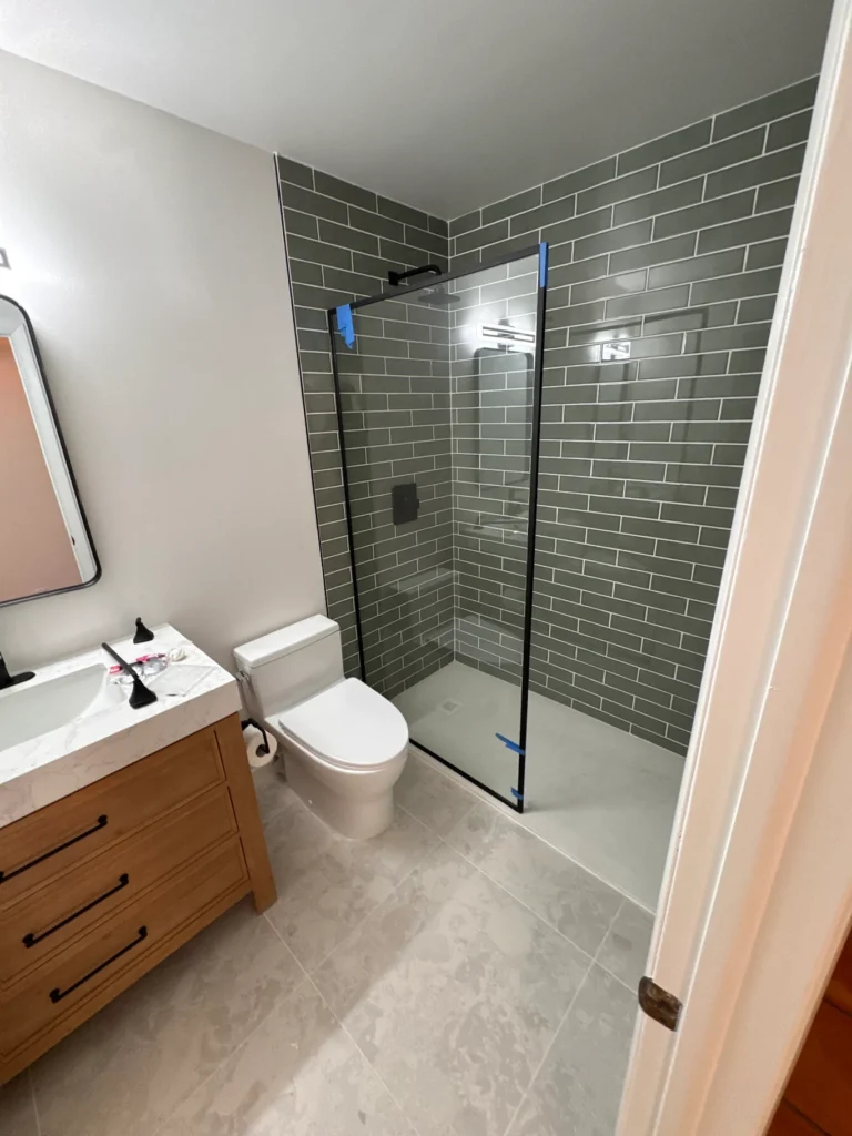 Frameless glass splash guard with matte black hardware in a Jupiter bathroom