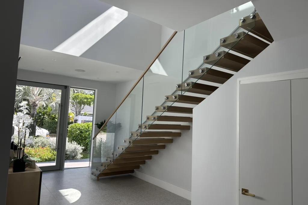 Glass railing with a wood cap on a floating staircase in West Palm Beach