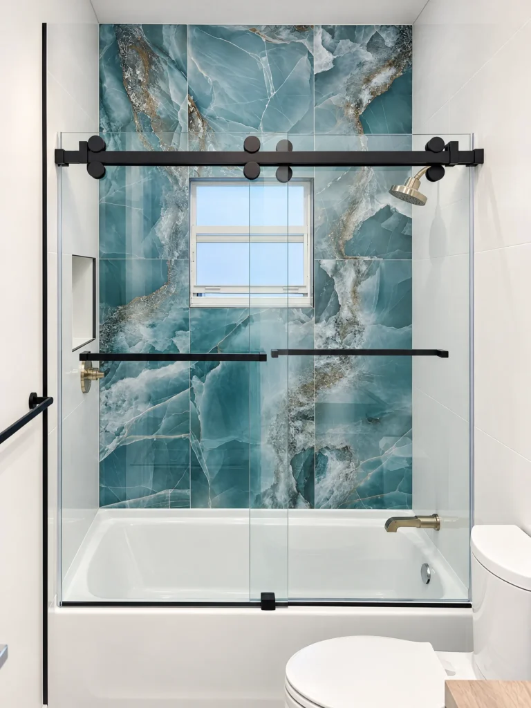 Cambridge sliding frameless tub enclosure with matte black rollers and blue marble tile