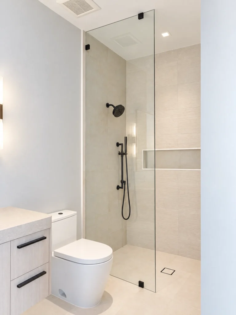 Frameless glass splash guard with matte black clamps for a walk-in shower