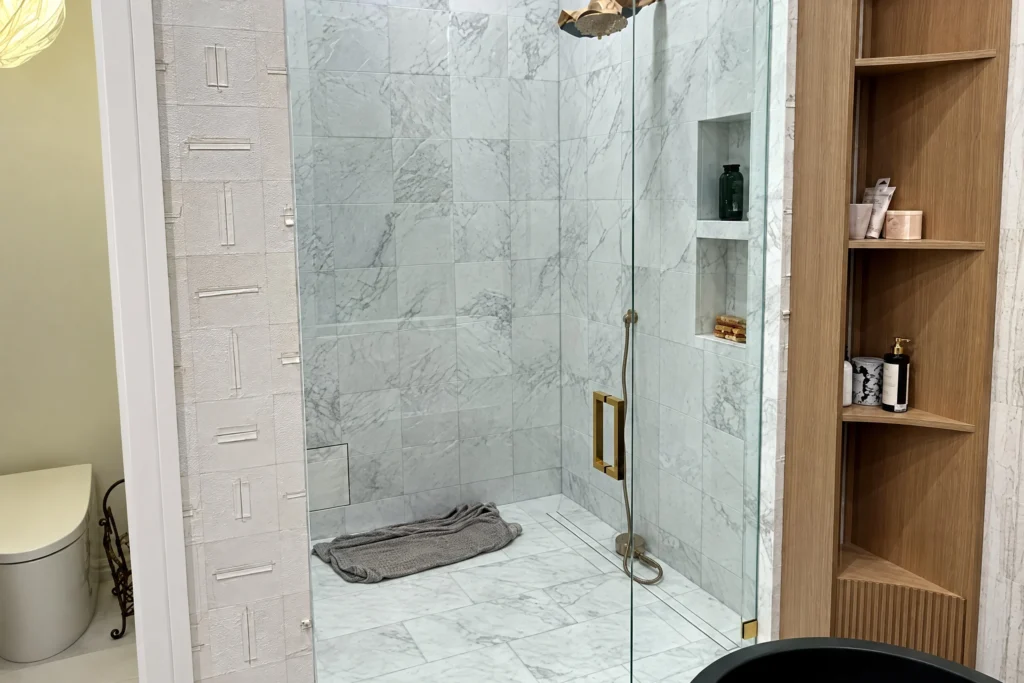 Frameless glass shower door and panel at the Addison Park Lane residence in Boca Raton, FL