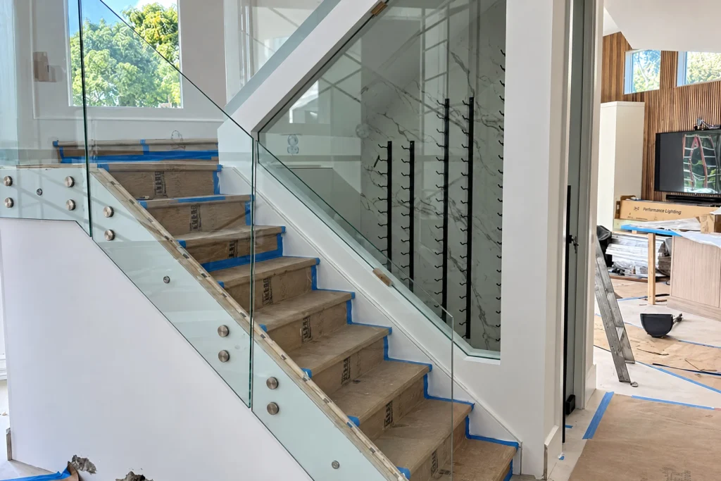 Interior glass staircase railing with white oak cap by ACG Glass & Metals in West Palm Beach