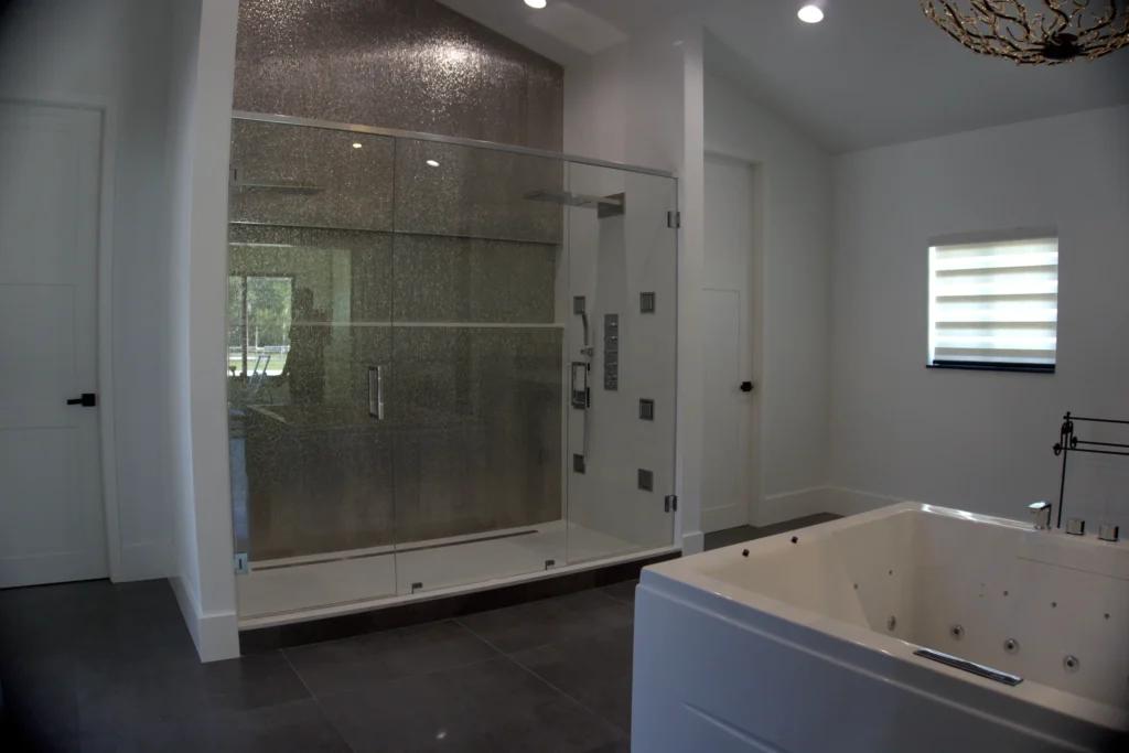 Frameless door and panel shower with polished chrome hardware in the primary bath, Audubon Trail Residence, Lake Worth, FL