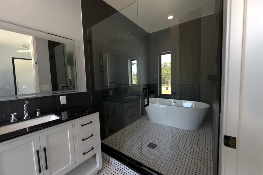 Frameless door and panel shower with matte black hardware enclosing a freestanding tub, Audubon Trail Residence, Lake Worth, FL