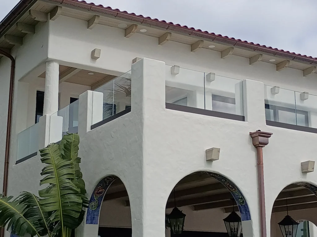 Frameless glass railing on the upper balconies of a waterfront home in Tequesta, FL by ACG Glass & Metals