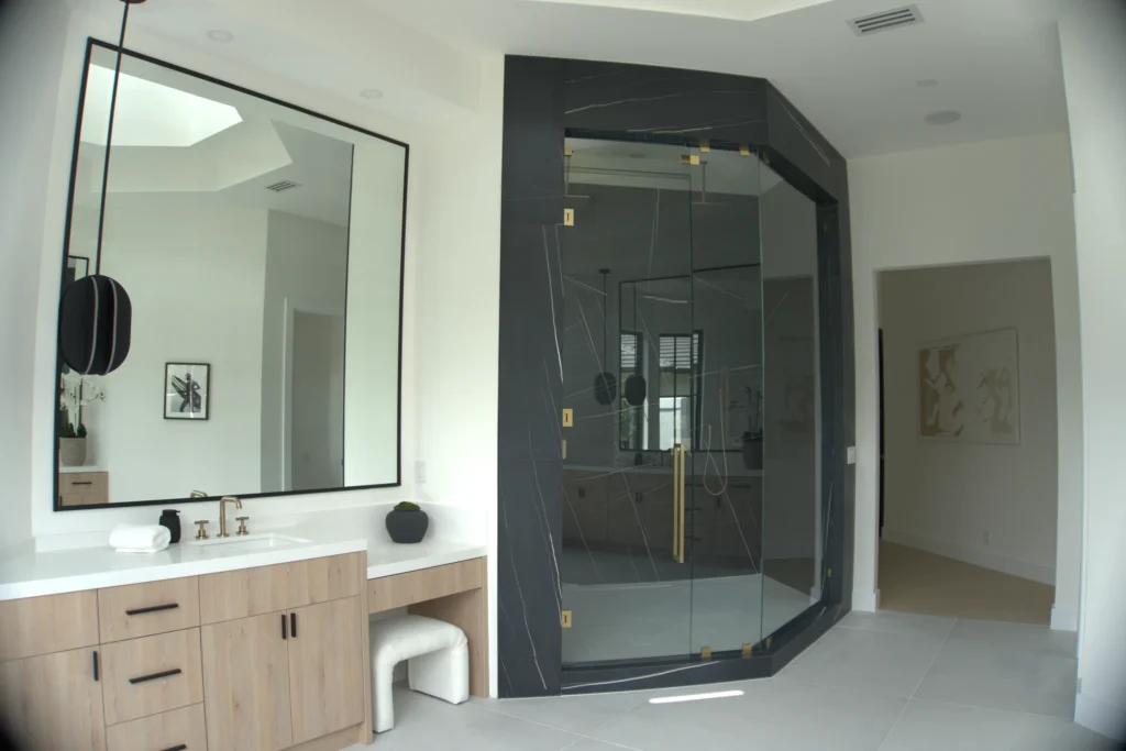 Frameless angle shower enclosure with satin brass hardware in a black marble master bath, Breakers West Blvd, West Palm Beach