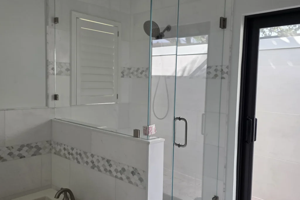 Frameless low iron 90 degree angle shower enclosure on a knee wall with brushed nickel hardware, North Palm Beach