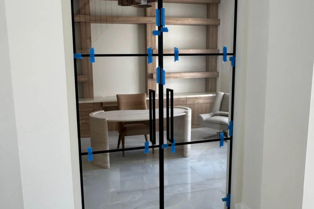Glass partition with double swing doors and matte black grids in a Palm Beach Gardens home office