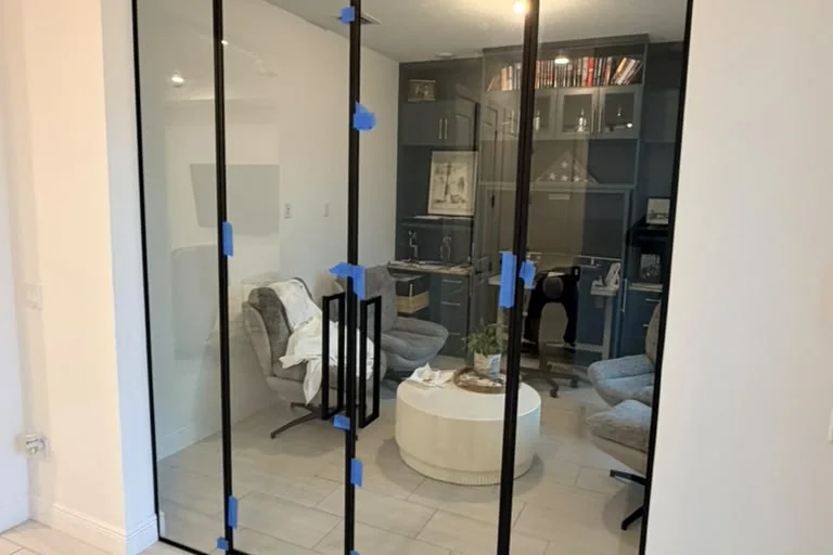 Framed glass partition with double swing doors and matte black frames in a Westlake home office