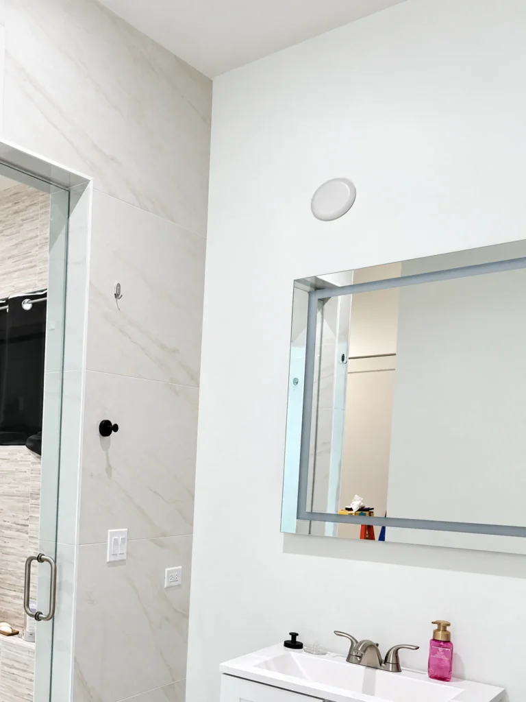 Frameless vanity mirror in a white bathroom, Kingfish Road residence