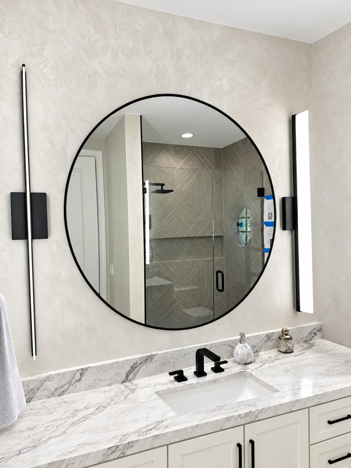 Round black framed mirror over a marble vanity