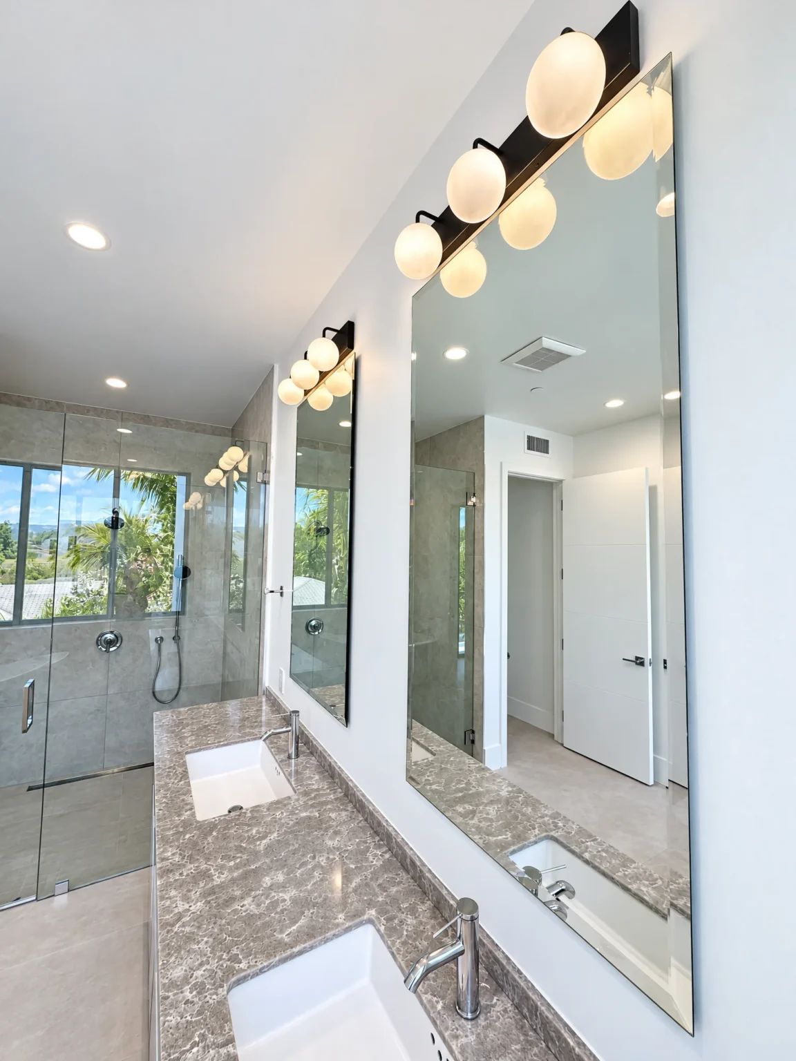 Clear vanity mirrors over a double vanity in a bright bathroom
