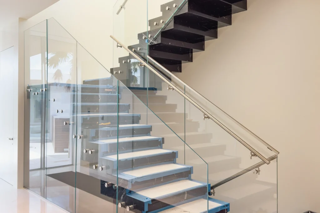 Frameless glass stair railing on brushed stainless standoffs with handrail through the glass, Del Lago Drive residence, Fort Lauderdale