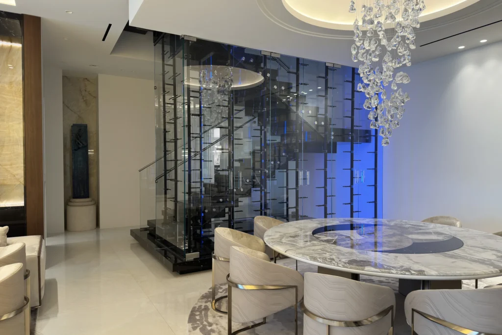 Floor to ceiling glass wine cellar enclosing the staircase beside the dining room of a Fort Lauderdale residence