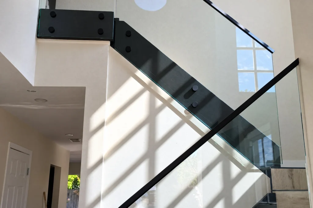 Interior glass stair railing on matte black standoffs with low profile top cap in an East Oakmont Circle residence, Hialeah