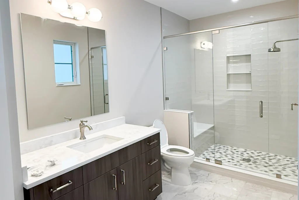 Guest bathroom with a custom clear vanity mirror and frameless glass shower in West Palm Beach