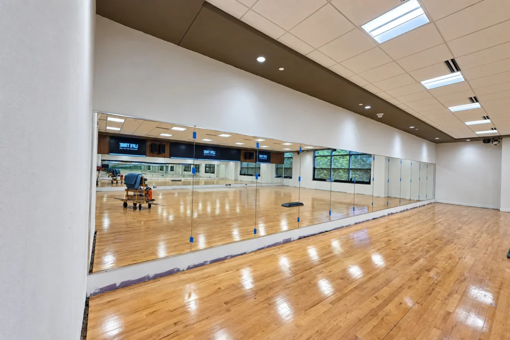 Frameless clear studio mirror wall with silver L metal at Life Time PBG Center, Palm Beach Gardens