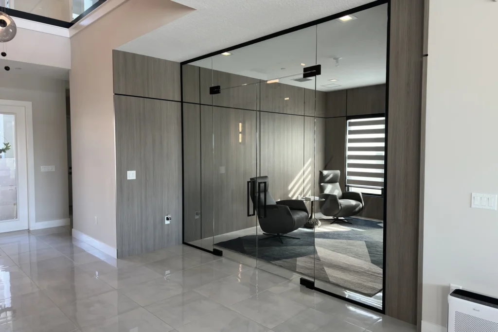 Frameless glass partition with glass door and black channels enclosing a home office, Migration Point Residence, Palm Beach Gardens, FL