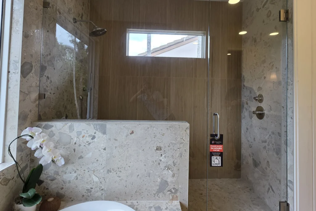Low iron frameless glass shower enclosure with brushed nickel hardware in a Mill Creek Drive residence, Palm Beach Gardens, FL