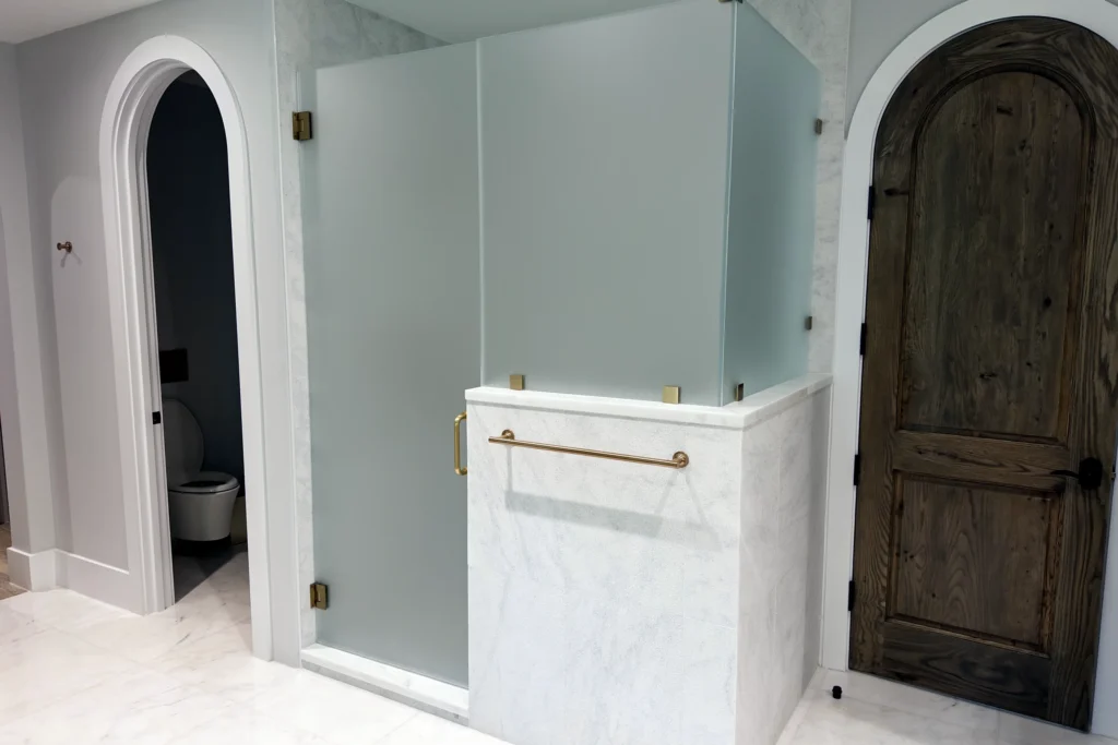 Frameless acid etched low iron glass shower with brushed bronze hardware, N Ocean Way Residence, Palm Beach