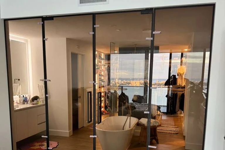 Bronze glass partition with matte black frame between a primary bedroom and bath, Miami FL