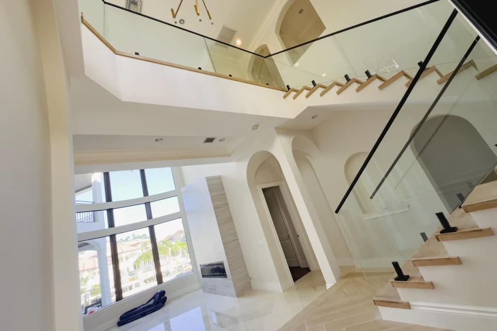 Frameless glass stair railing with spigots and black cap rail at NE 6th Dr residence in Boca Raton, FL by ACG Glass & Metals