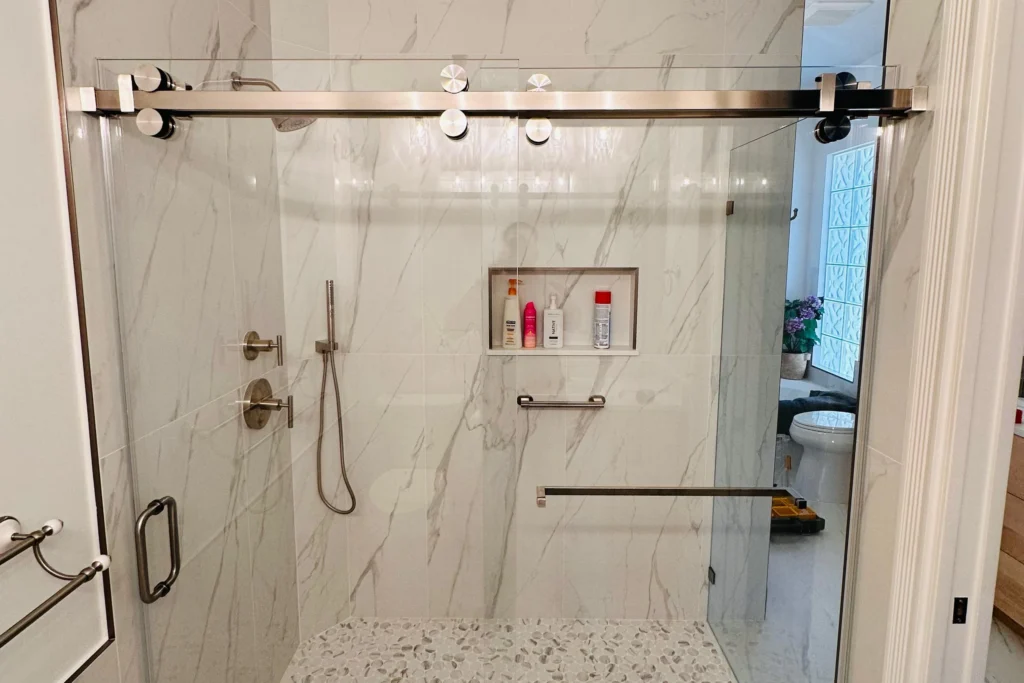 Low iron frameless sliding shower enclosure with brushed nickel hardware, Niemen Drive residence, Palm Beach Gardens