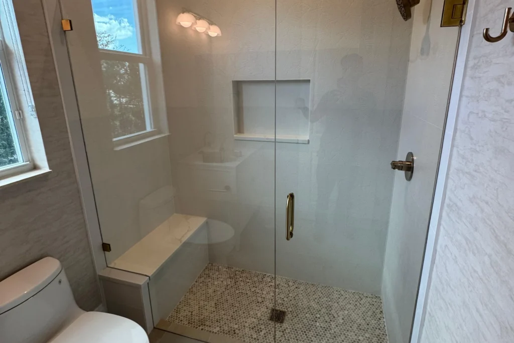 Frameless glass shower enclosure with satin brass hardware on SE Old Plantation Circle in Jupiter, FL by ACG Glass & Metals