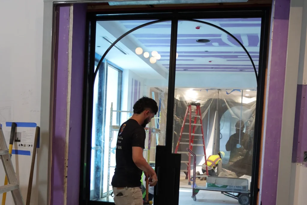 Custom arched black aluminum glass French doors being installed at the Polo Club in Boca Raton
