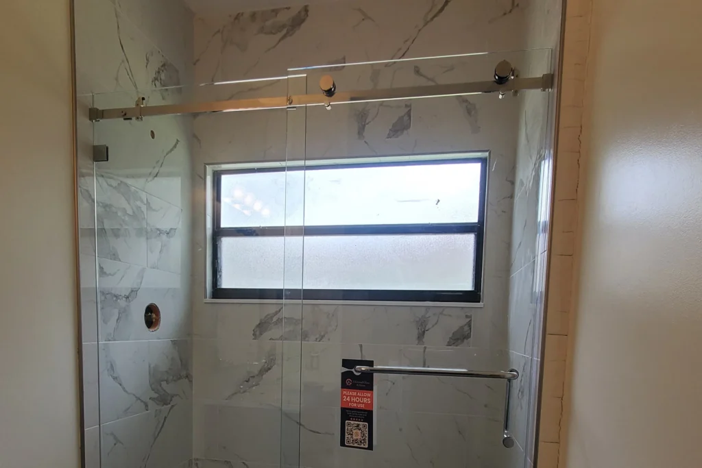 Serenity sliding frameless glass shower enclosure with polished chrome hardware in a Wellington bathroom