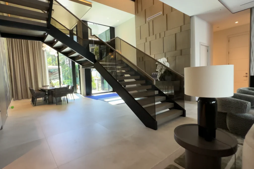 Floating stair with bronze laminated glass railing and white oak cap in a Highland Beach home