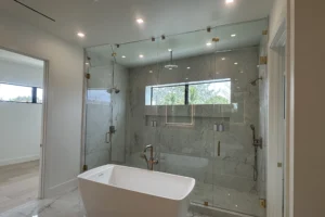 Frameless glass shower enclosure with brushed gold hardware in a Boca Raton home