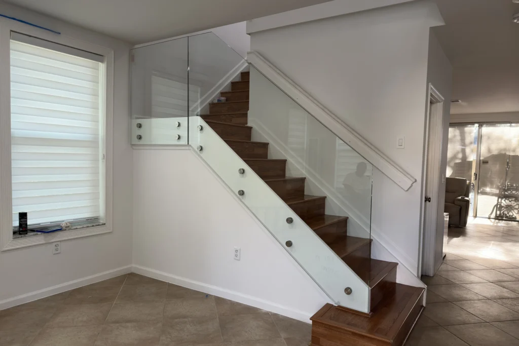 Interior glass railing with standoffs on the stair and base shoe on the landing, SW 48th St residence in Miramar, FL, by ACG Glass & Metals